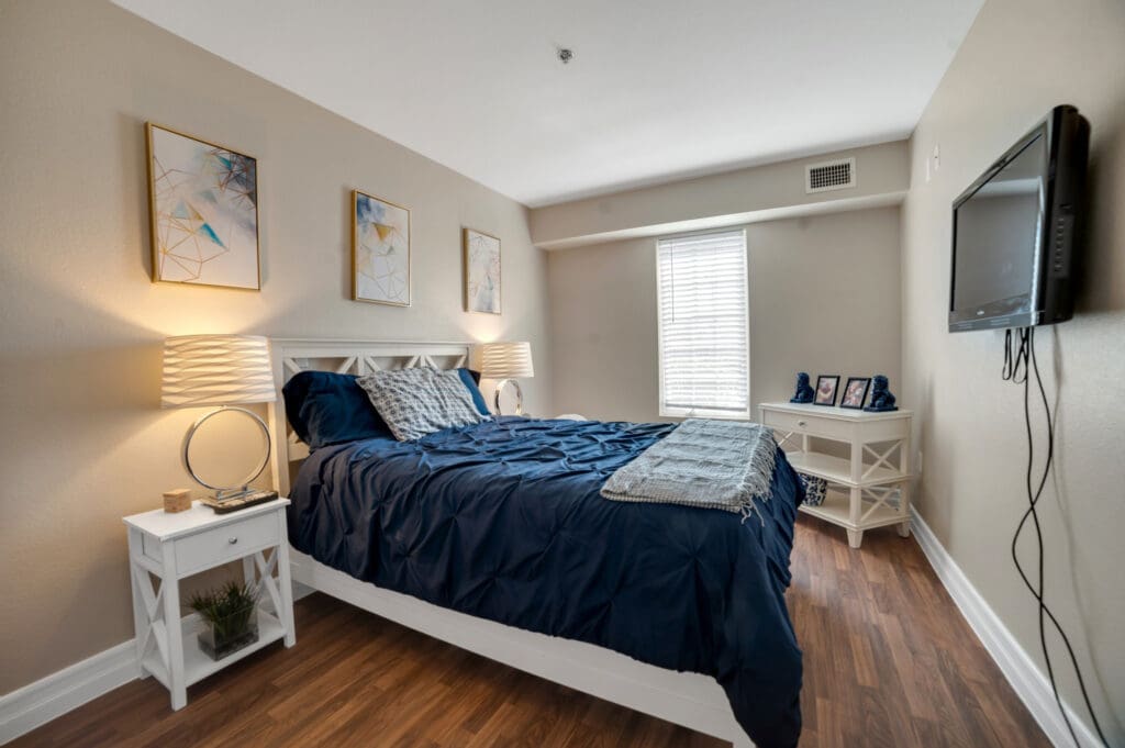 acaciaHDR-61 - Acacia Springs Resident bedroom with navy bedding and white furniture at Acacia Springs, a senior living community.